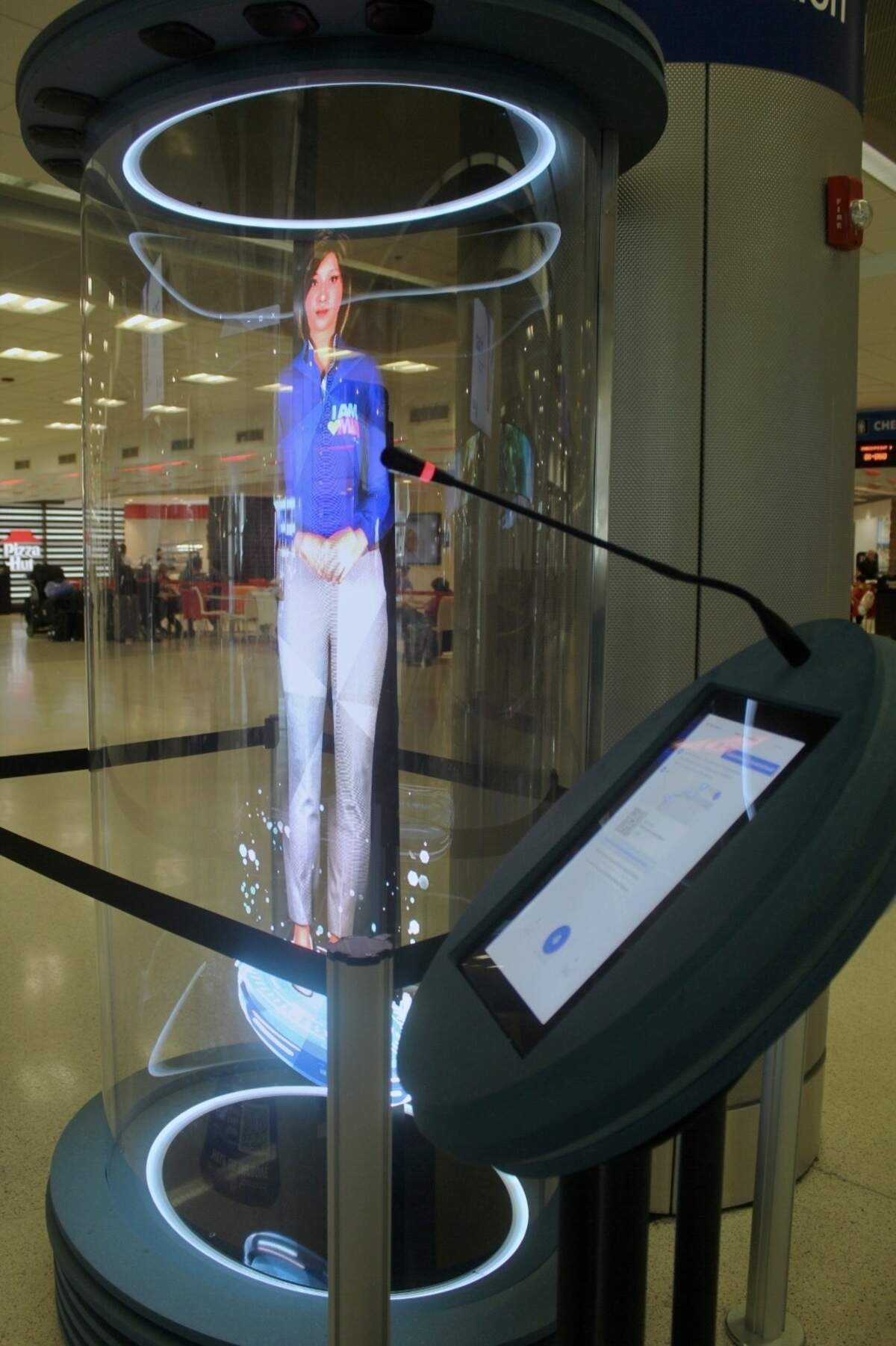 To use the AI hologram assistant, one must hold down the microphone icon on the screen beside it and speak aloud their request. This is one of four Miami International Airport employee avatars used by the holograms, taken at MIA on July 1, 2026.