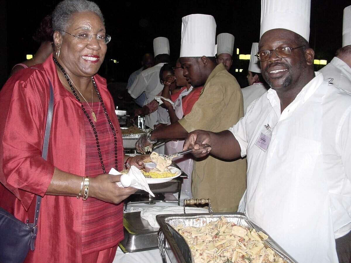 In this file photo from June 12, 2001, Alexandria Holloway, then academic dean at the Miami Dade College Wolfson Campus was served by Wayne Rogers, a fire fighter with the Miami-Dade Fire Department turned chef, at the Something's Cooking in Overtown Gala held at the Wolfson’s atrium.