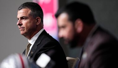 Miami (FL) Hurricanes head coach Mario Cristobal listens to Ohio State Buckeyes head coach Ryan Day talk to media during a Cotton Bowl press conference at AT&T Stadium in Arlington, Texas prior to their College Football Playoff quarterfinal matchup on Dec. 30, 2025.
