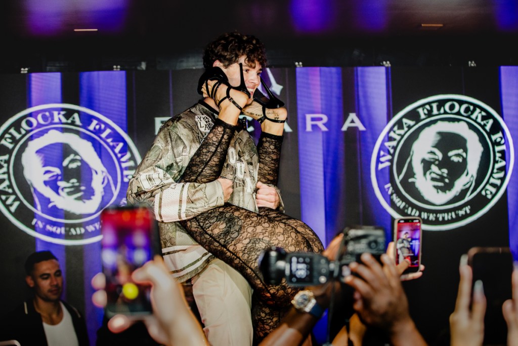 A photo of a man on a stage holding a woman upside down