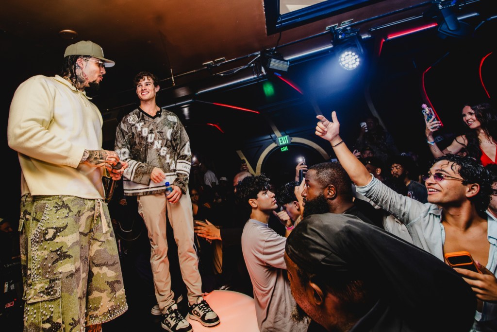 A photo of two men on a stage dancing in front of a crowd. 