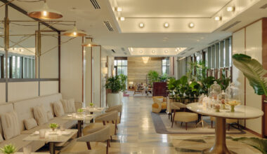 Honey Fitz café and champagne bar interior with beige seating, copper pendant lights, and tropical plants