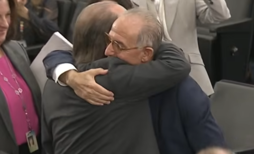 Two older men embrace