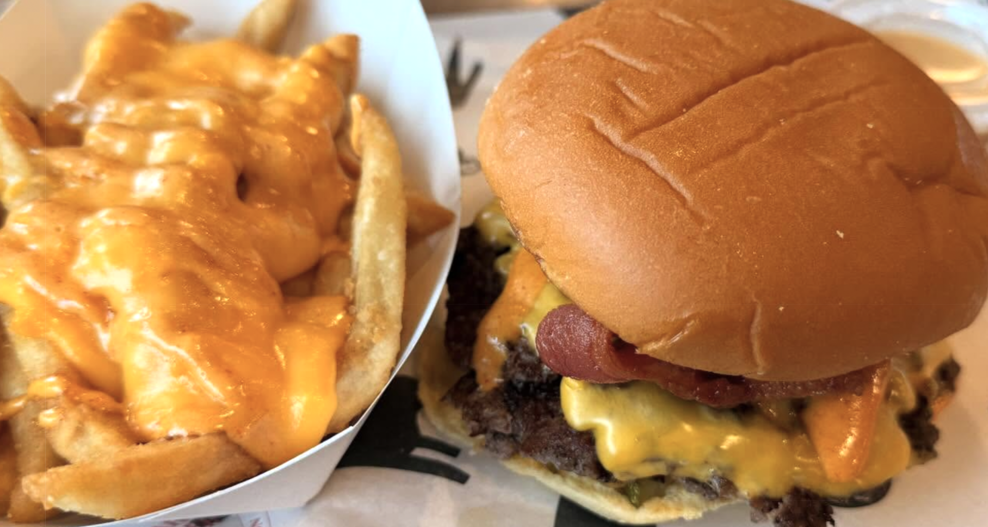 a cheese burger and a side of fries smothered in yellow cheese
