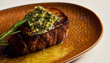 a filet mignon with green sauce on a gold plate