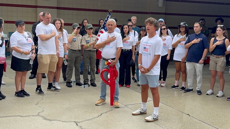 Dennis Nieves, 17, a student at Oasis High School in Cape Coral, signs the national anthem Sunday at the 27th Big Backpack Event. Despite rain and lightning the event went off without a hitch Sunday with thousands of backpacks filled with school supplies and bags of groceries distributed at the Skatium in Fort Myers. With Nieves is Leonardo Garcia, founder of the Multicultural Centre and originator of the event.