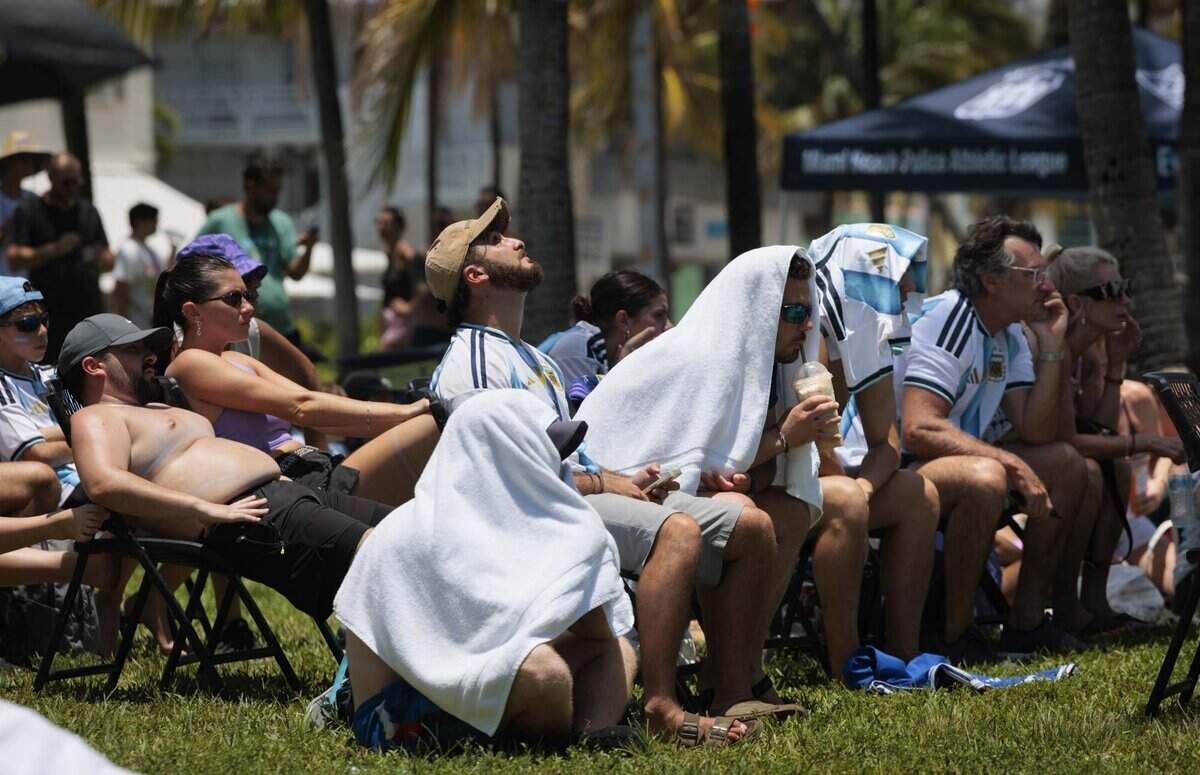 Fans cover themselves from the sun as they watch the FIFA World Cup at a watch party during a heat advisory as they watch Argentina play Egypt on Tuesday, July 7, 2026, at Lummus Park in Miami Beach, Fla.