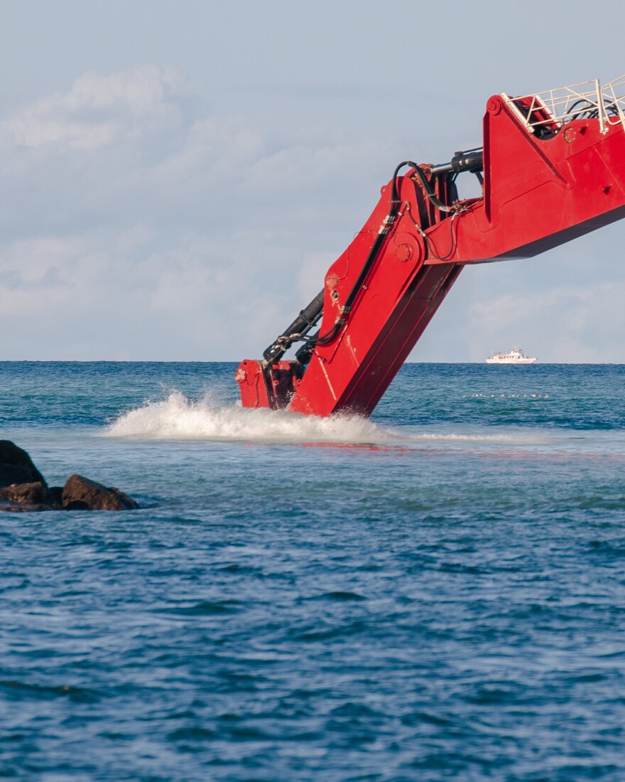 A crane arm dives into the water off of Fort Lauderdale beach.