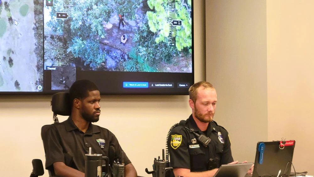 Police officers sit at a table operating a drone.