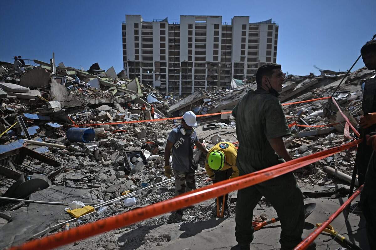 Rescue workers and volunteers look for missing people amid the rubble at Los Cocos beach, in Caraballeda, La Guaira state, Venezuela, on July 1, 2026, following the June 24 twin earthquakes. Venezuelans, with help from around the world, were still searching on July 1, 2026 for survivors a week after massive earthquakes killed nearly 2,000 and left thousands unaccounted for. (Photo by Juan BARRETO / AFP via Getty Images)