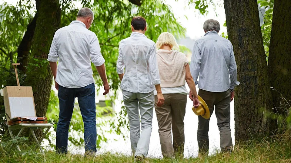 Group of seniors from behind go to a lake in summer