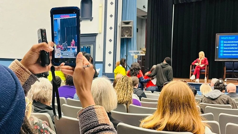 Mayor Donna Deegan sitting on a stage at a town hall meeting