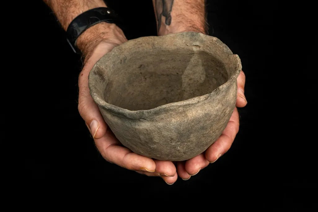 A pair of hands cupping a piece of pottery