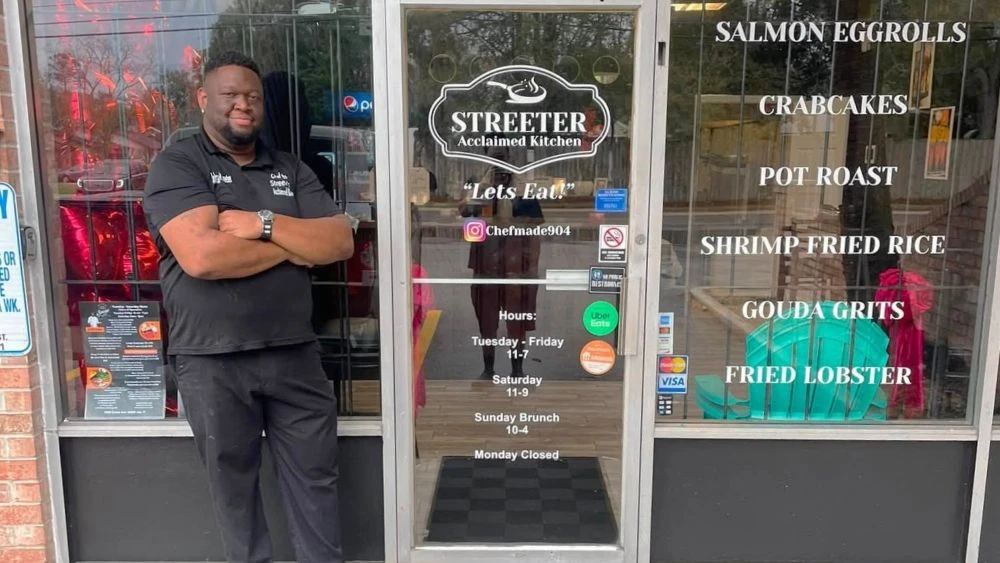 Johnathan Streeter, owner of Streeter Acclaimed Kitchen, stands in front of his restaurant with his arms crossed.