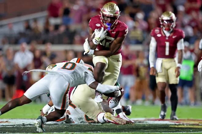 TALLAHASSEE, FLORIDA - OCTOBER 4: Ousmane Kromah #32 of the Florida State Seminoles tries to jump over Keionte Scott #0 of the Miami Hurricanes in the second quarter of the game at Doak S. Campbell Stadium on October 4, 2025 in Tallahassee, Florida. (Photo by Jason Clark/Getty Images)