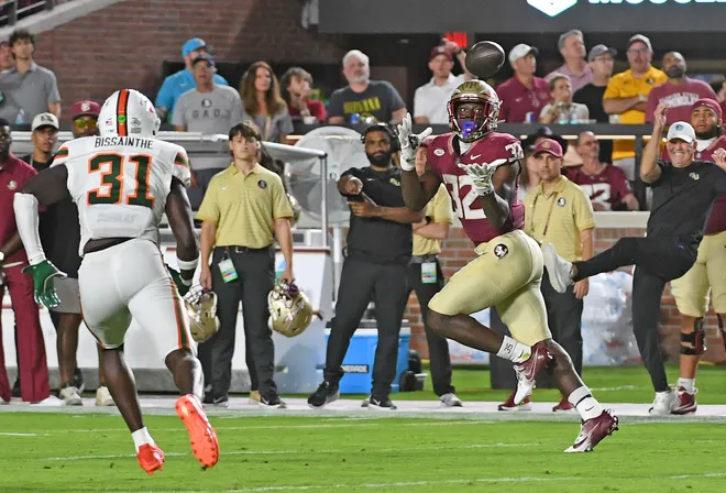 Oct 4, 2025; Tallahassee, Florida, USA; Florida State Seminoles running back Ousmane Kromah (32) makes a catch against Miami Hurricanes linebacker Wesley Bissainthe (31) during the first half at Doak S. Campbell Stadium. Mandatory Credit: Robert Myers-Imagn Images