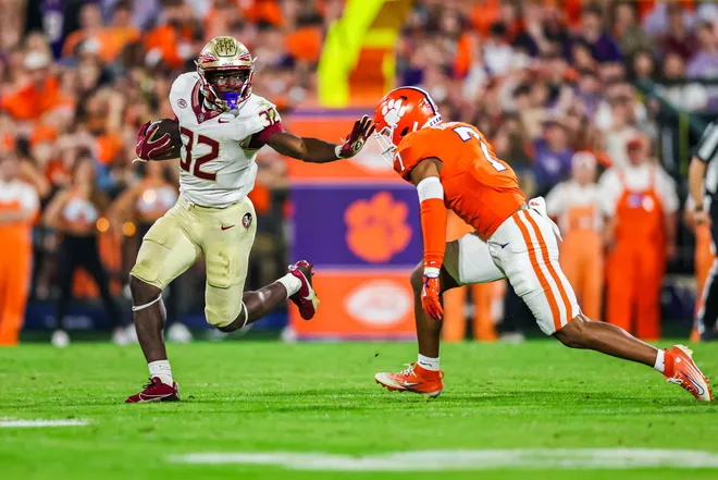 CLEMSON, SOUTH CAROLINA - NOVEMBER 08: Ousmane Kromah #32 of the Florida State Seminoles escapes a tackle by Khalil Barnes #7 of the Clemson Tigers during the first half of a football game at Memorial Stadium on November 08, 2025 in Clemson, South Carolina. (Photo by David Jensen/Getty Images)