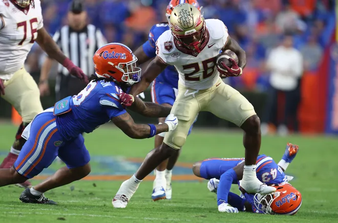 Florida State running back Samuel Singleton Jr. (28) gains yards against Florida defensive end Kamran James (24) and steps on Florida defensive back Alfonzo Allen Jr. (43) during the first half of an NCAA football game at Steve Spurrier Field at Ben Hill Griffin Stadium in Gainesville, FL on Saturday, November 29, 2025. [Alan Youngblood/Gainesville Sun]