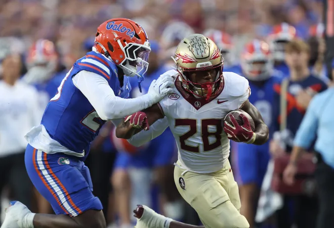 Florida State running back Samuel Singleton Jr. (28) gains yards against Florida defensive end Kamran James (24) during the first half of an NCAA football game at Steve Spurrier Field at Ben Hill Griffin Stadium in Gainesville, FL on Saturday, November 29, 2025. [Alan Youngblood/Gainesville Sun]
