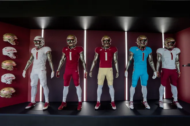 The football uniforms are displayed on mannequins inside the Florida State University Dunlap Football Center.