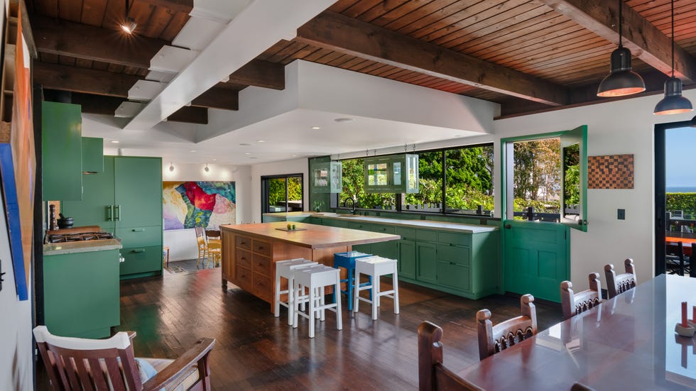 Modern kitchen with green cabinets and open windows.