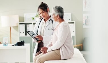 Doctor reviews medical information on a tablet with a patient during an outpatient clinic visit.