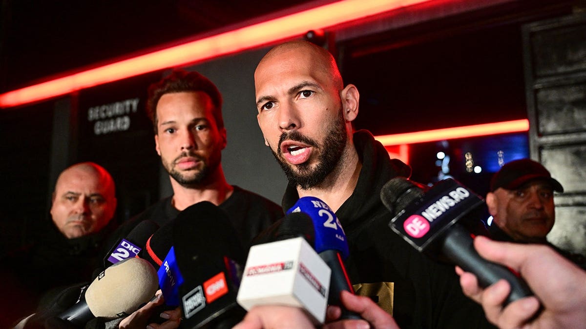 Andrew Tate speaks to the media beside Tristan Tate in Bucharest.