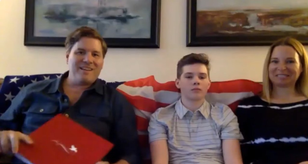 A photo of a young boy flanked by his parents on a couch.
