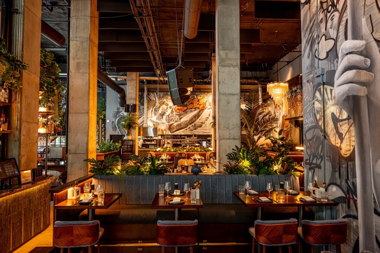 Interior of V Modern Italian in Nashville featuring warm lighting, marble features and murals of Italian sculptures