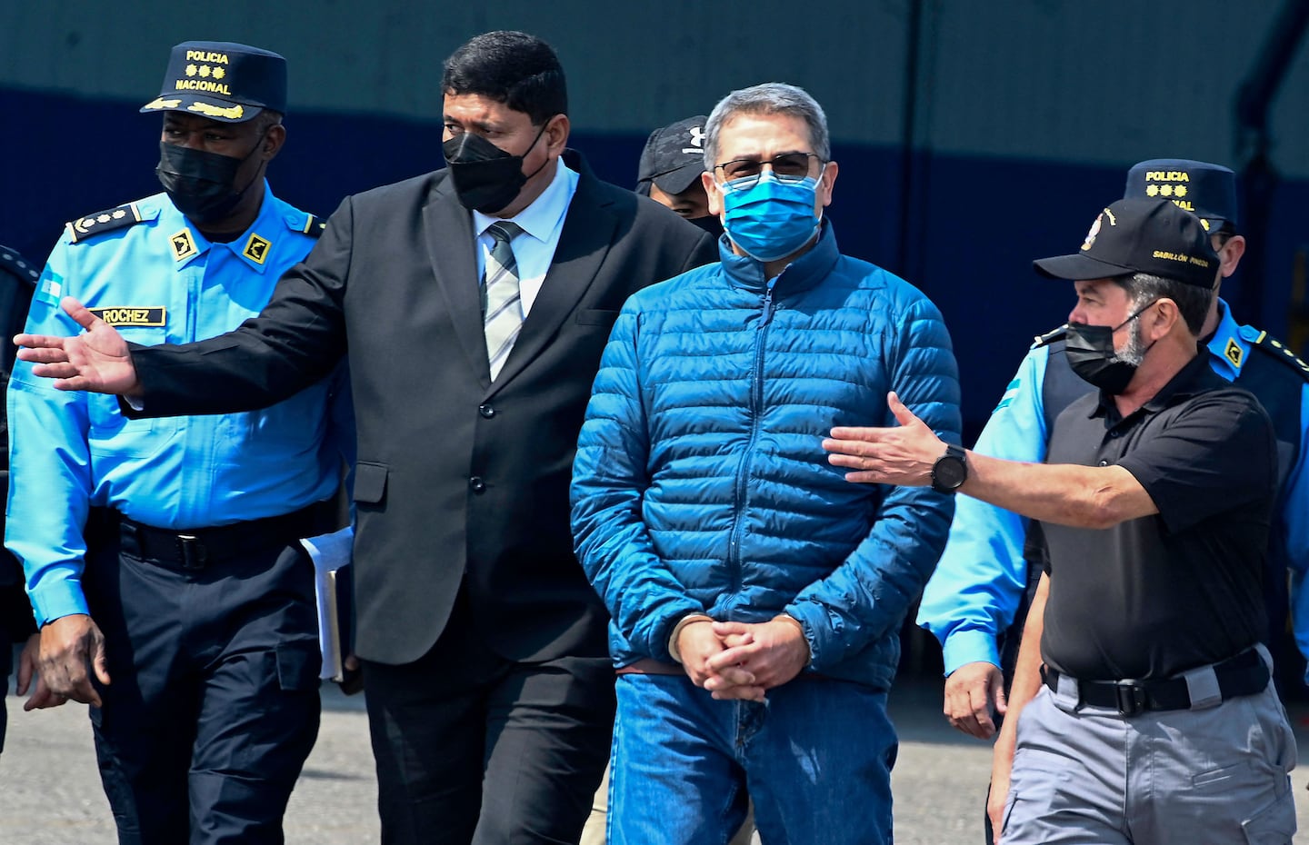 Honduras' former President Juan Orlando Hernandez (2-R) is escorted by Minister of Security Ramon Sabillon (R) towards a plane of the US Drug Enforcement Agency (DEA), during his extraditaton to United State at the Air force Base, in Tegucigalpa, on April 21, 2022.