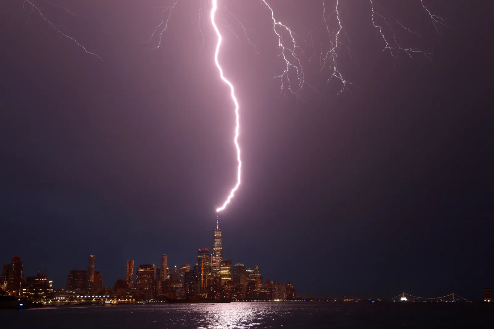 Lightning strikes One World Trade Center as the sun sets in New York City on July 03, 2026, as seen from Hoboken, New Jersey.