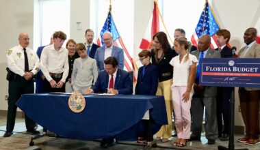 Florida Gov. Ron DeSantis signs the 2026-27 state budget during a ceremonial event surrounded by lawmakers, community leaders and children.