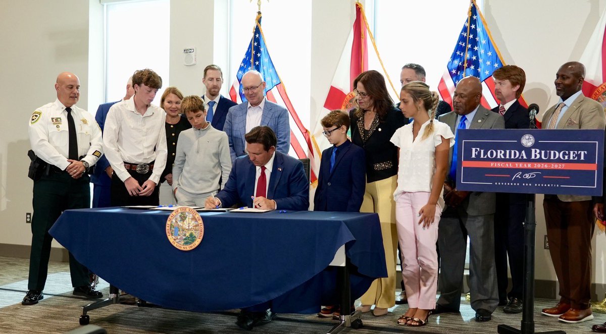 Florida Gov. Ron DeSantis signs the 2026-27 state budget during a ceremonial event surrounded by lawmakers, community leaders and children.
