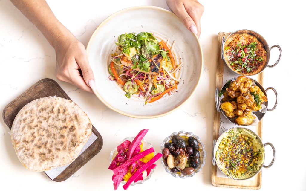hands holding a dish surrounded by other dishes with a white background