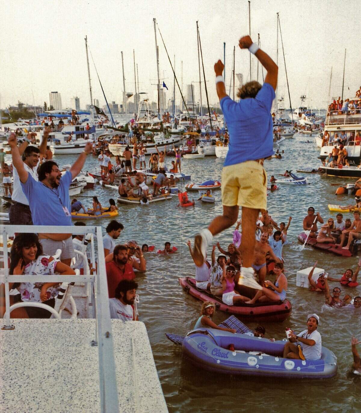 Singer Jimmy Buffett jumps into the water from the stage in 1985 as fans on boats surround Miami Marine Stadium.