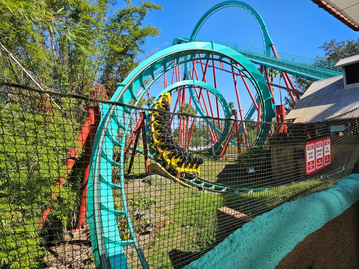 A yellow and black coaster train maneuvers through the teal steel track of Kumba