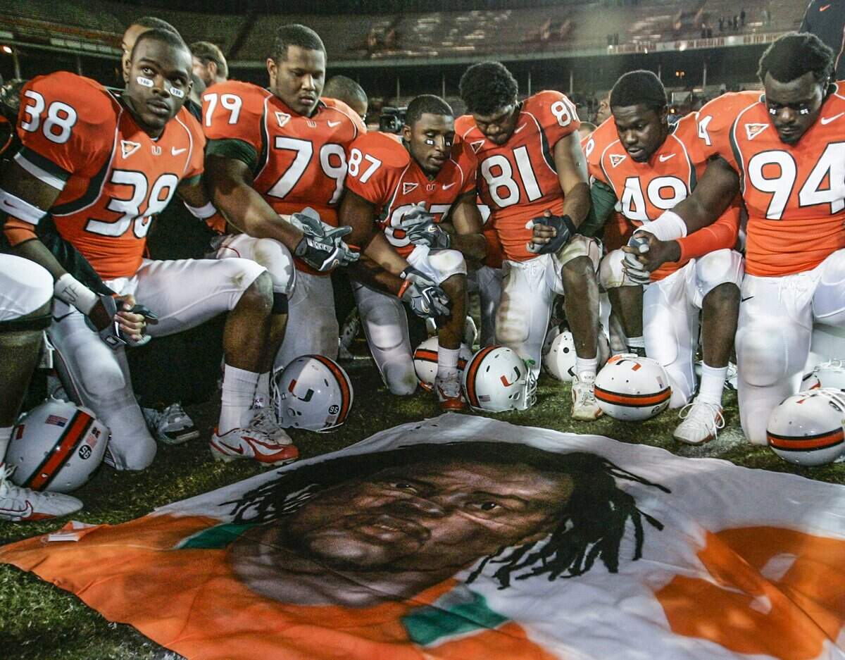 University of Miami football players, including Rashaun Jones (38) at left, hold hands at mid-field in front of a mural of teammate Bryan Pata after game against Boston College at the Orange Bowl Stadium in Miami on November 23, 2006. Jones was arrested Thursday, August 19, 2021 in connection with the fatal shooting of his teammate, Bryan Pata.
