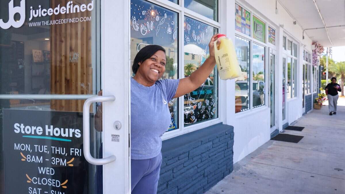 Fathiyyah “Tia” Doster, owner of JuiceDefined, stands at the front door of her Opa-locka juice bar, Thursday, July 30, 2026, in downtown Opa-locka, Fla.