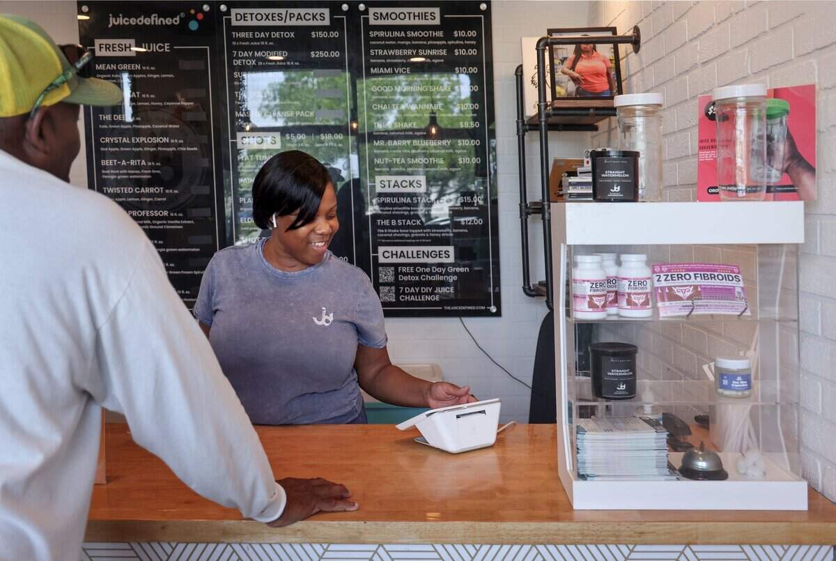 Customer Michael Witcher chats with Fathiyyah “Tia” Doster, owner of JuiceDefined, as he makes his regular purchase of pressed juice at her Opa-locka juice bar, Thursday, July 30, 2026, in downtown Opa-locka, Fla.
