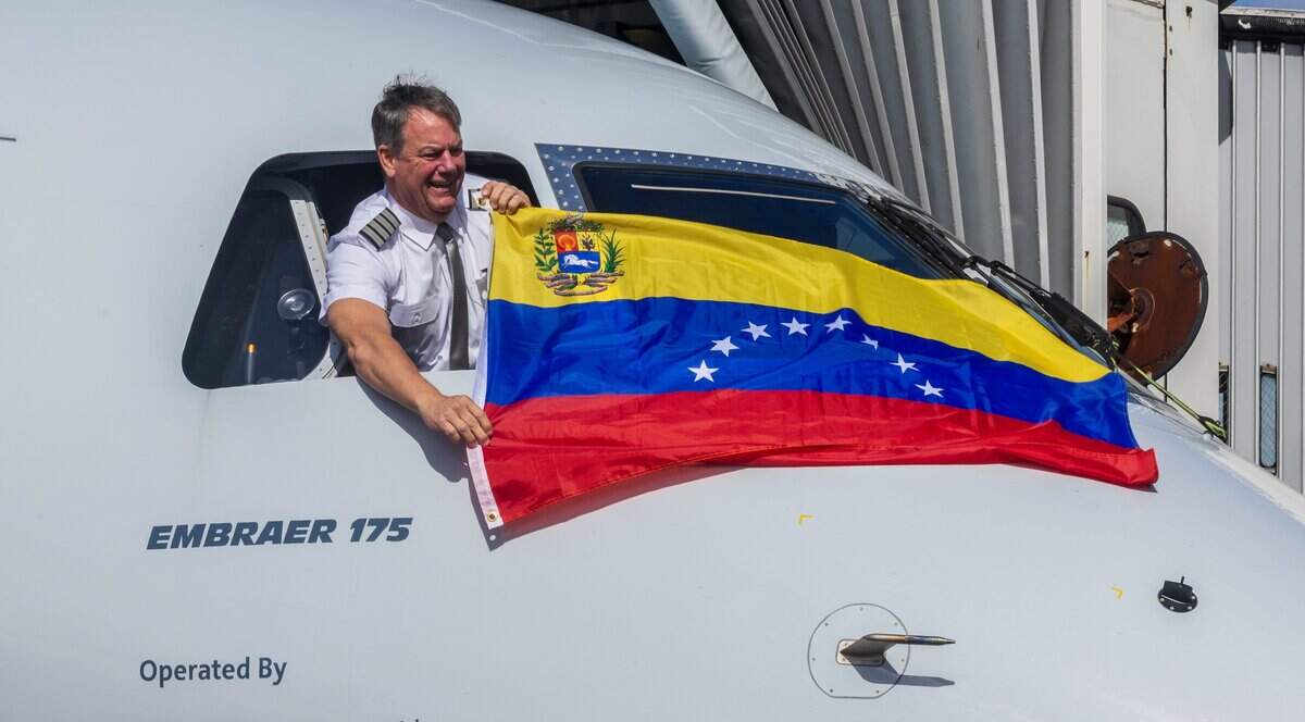 Captain Robert Nieder waves a Venezuelan flag from the cockpit of the first American Airlines Embraer E-175 aircraft, departing from MIA to Maracaibo, Venezuela since the service was suspended in 2019, on Tuesday July 14, 2026.
