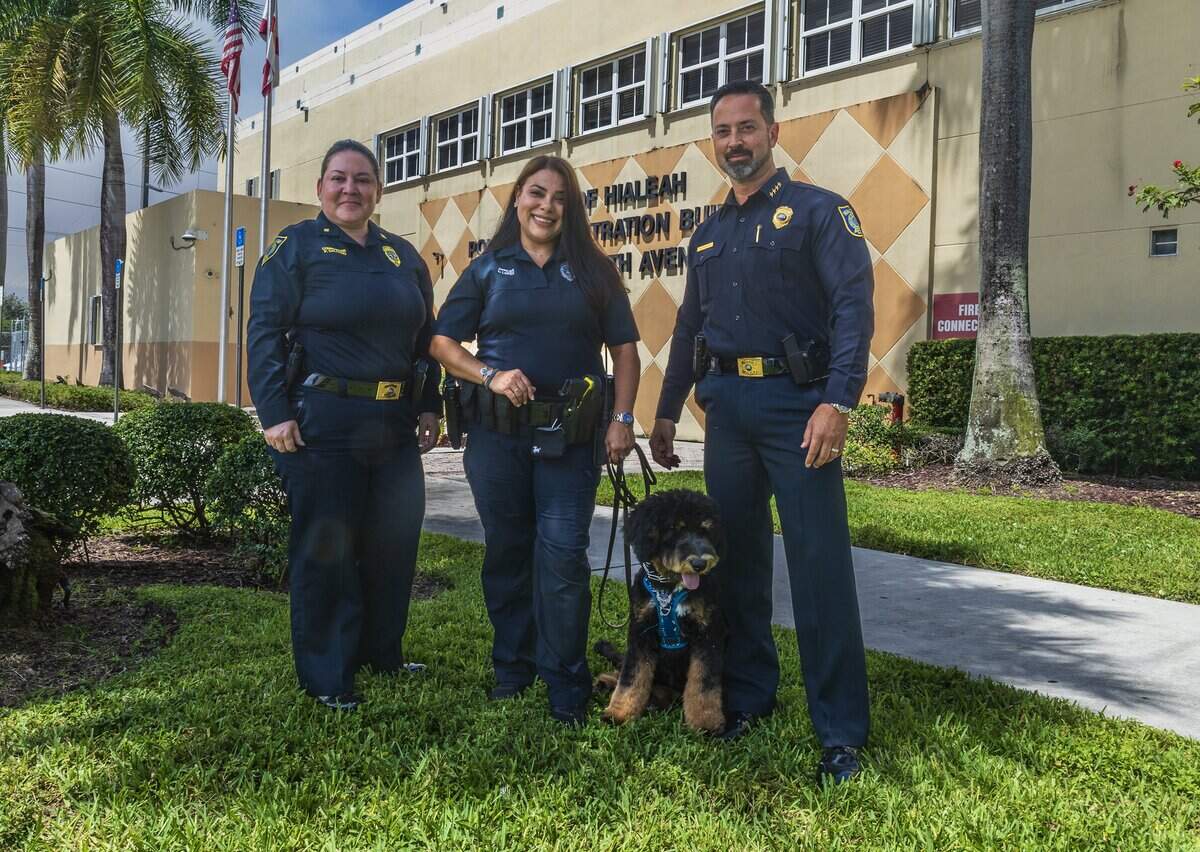 Hialeah Police Department Commander Patricia Salgado, far left, and Chief of Police George Fuente, flank Officer Lucicarmen Lopez and Domino, the official Hialeah Police Therapy Dog at police headquarters on June 16, 2026.