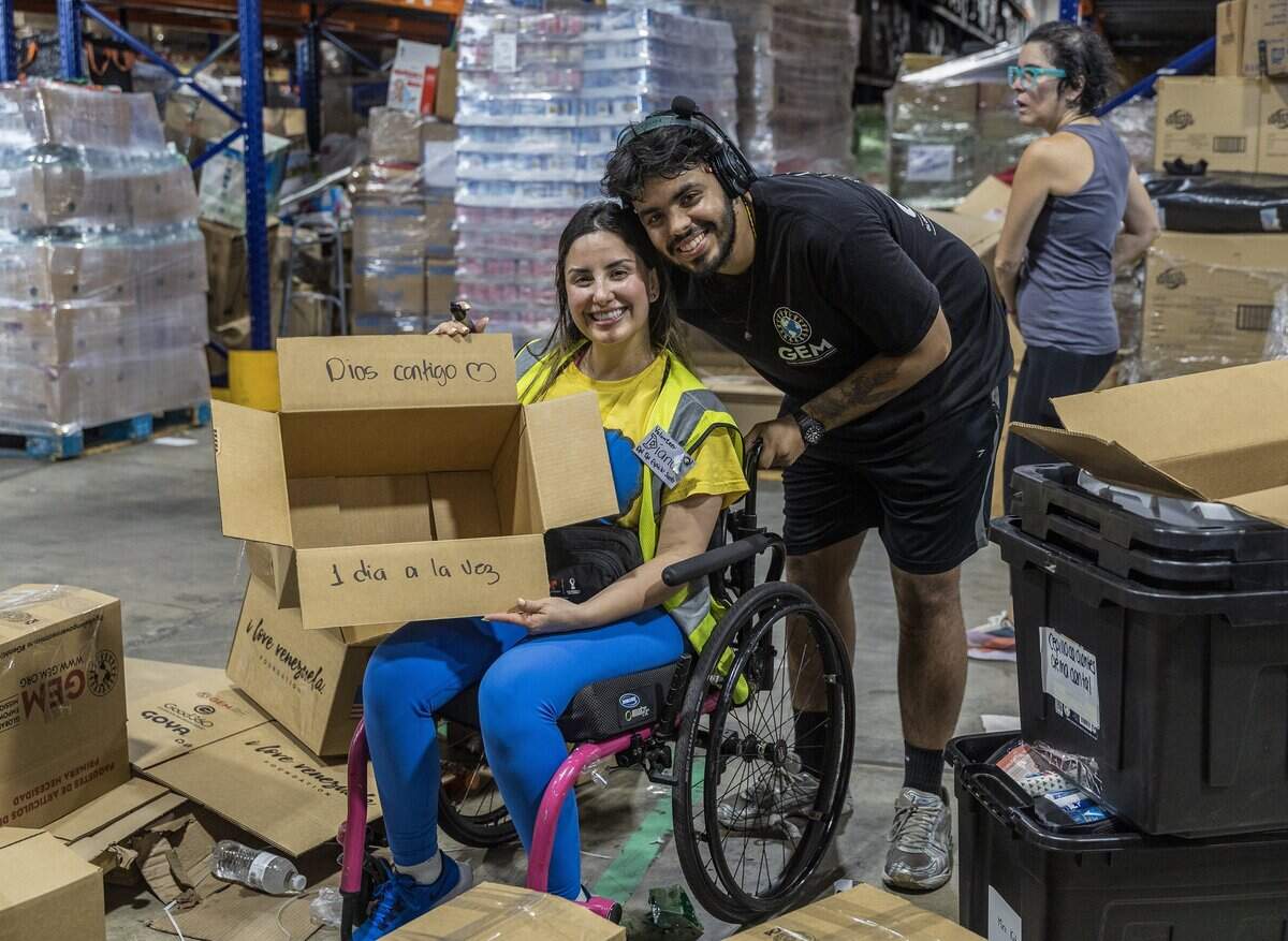 Volunteer Ibrahim Reyes greets Claudia Chacon as she writes messages of hopes on boxes with supplies of aid for the victims in Venezuela following the earthquakes, as a press conference held by Michael Capponi, Global Empowerment Mission (GEM), was taking place to announce the long time commitment the plans for GEM to settle permanently in La Guaira, at the organization's headquarters in Doral, on Friday July 17, 2026.