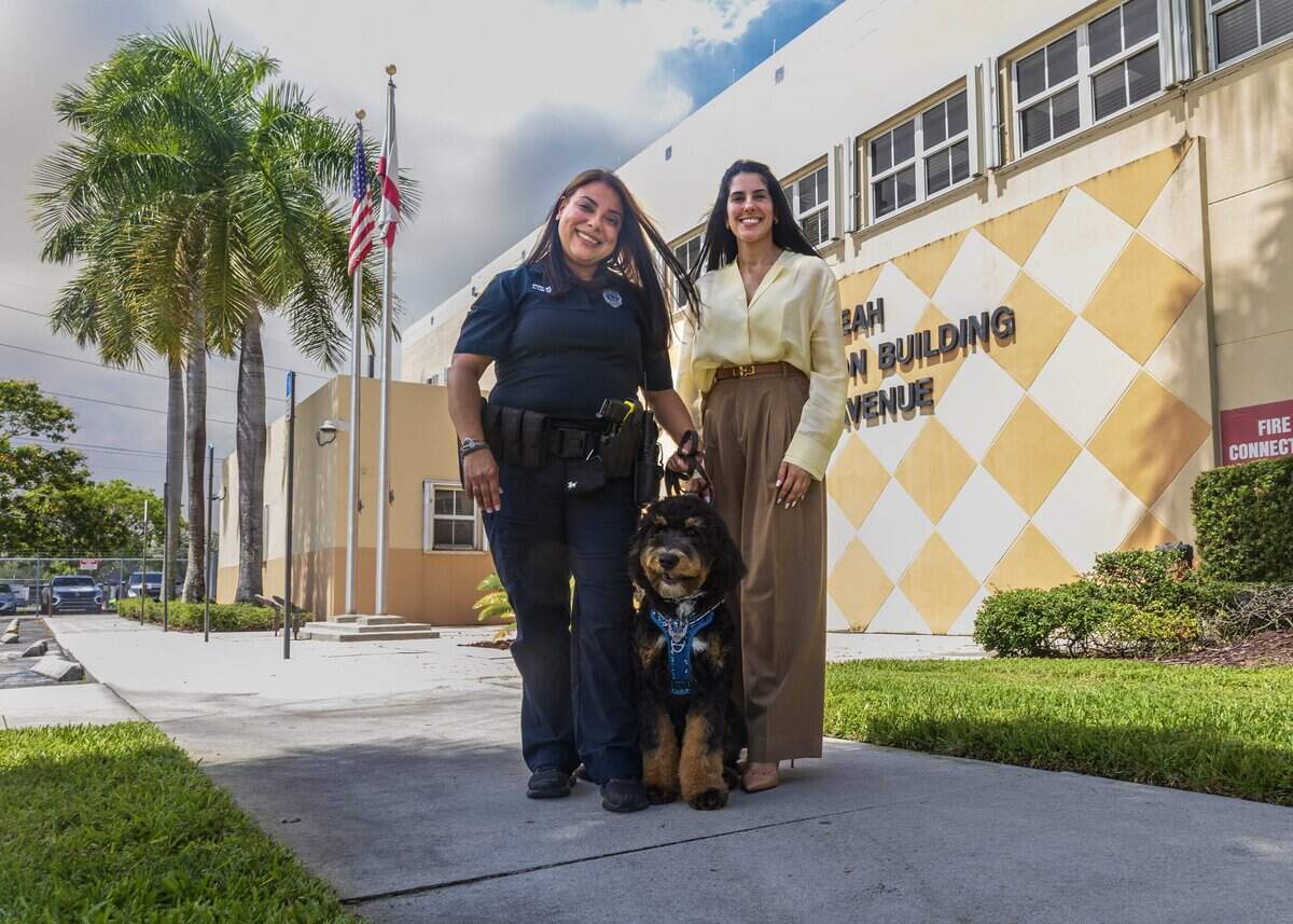 Hialeah Council member Gelien Perez poses with officer Lucicarmen Lopez and Domino, the official Hialeah Police Therapy Dog, at police headquarters on June 16, 2026.