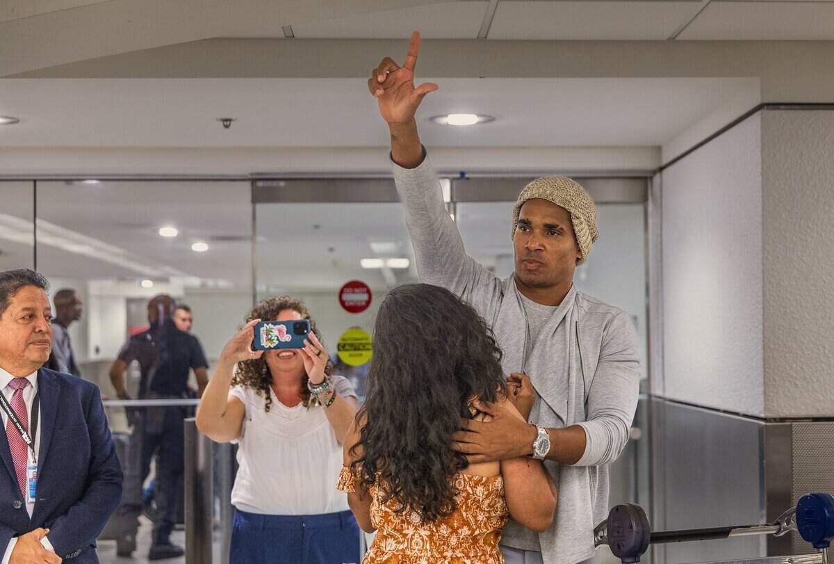Cuban dissident artist Luis Manuel Otero Alcántara hugs his friend Anamely Ramos and puts up a “liberty” hand signal as he arrives at Miami International Airport on Saturday.