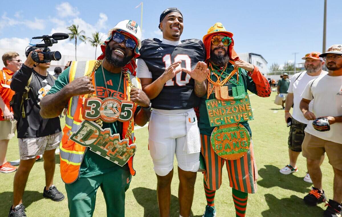 Miami Hurricanes fans JD Da Boss, at left, and Bobby Johnson, right, pose for photos with quarterback Darian Mensah (10) after UM's spring football game at Cobb Stadium on the University of Miami campus in Coral Gables, Florida, on Saturday, April 18, 2026.