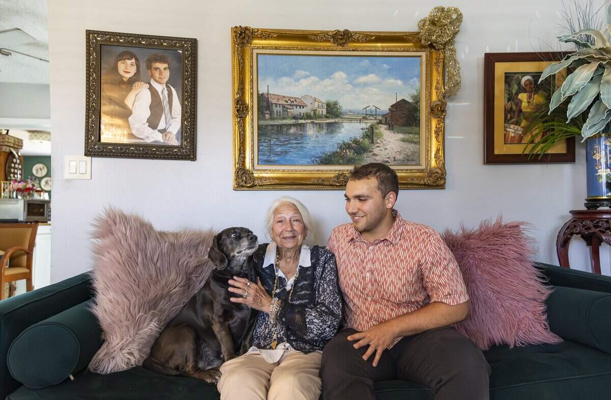 Alberto Rosales, 23, his grandmother, Susie Rosales, 86, and their dog, Coco, sit on their couch while at their home on Friday, May 15, 2026, in Miami, Fla.
