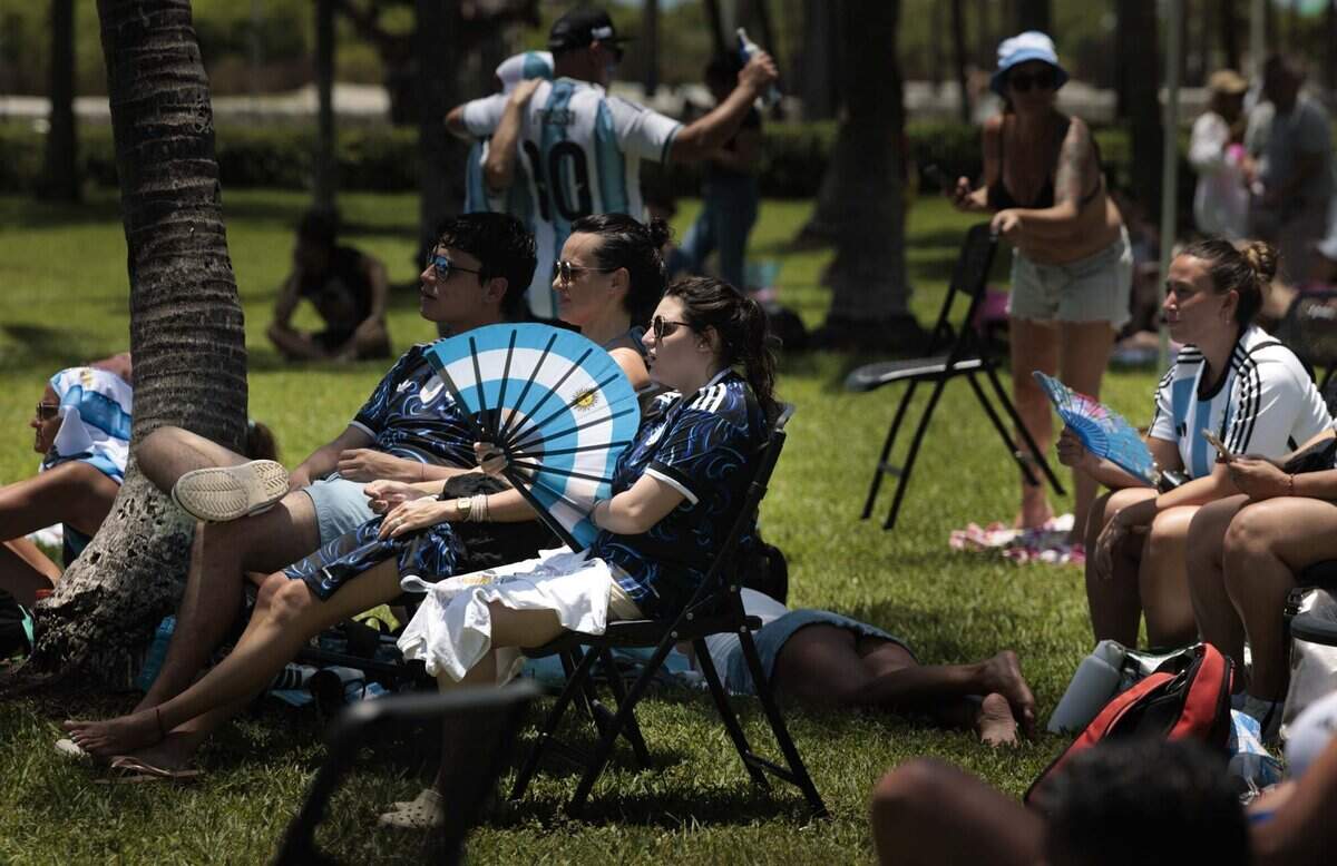 Attendees fan themselves off at a watch party during a heat advisory as they watch Argentina play Egypt in the FIFA World Cup on Tuesday, July 7, 2026, at Lummus Park in Miami Beach, Fla.