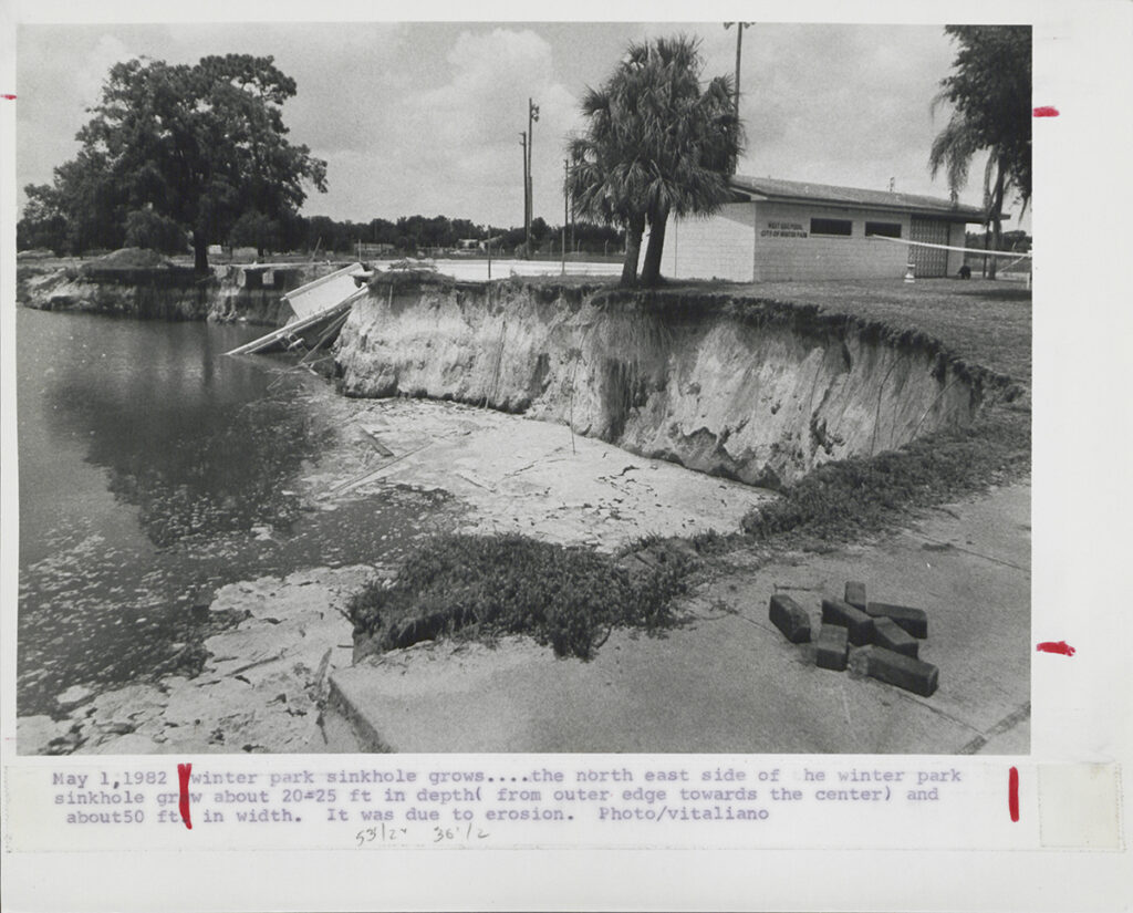Black and white photo with sinkhole in the foreground and swimming pool behind