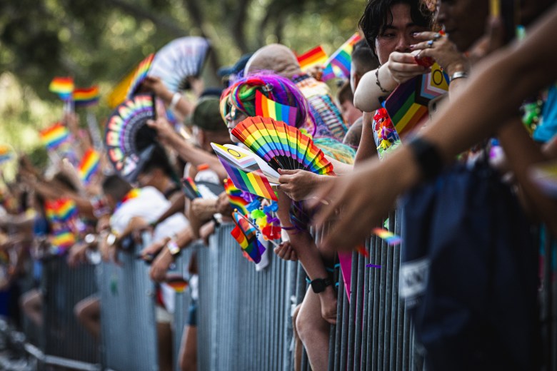 People holding rainbow Pride fans and flags at the gates of St. Pete Pride