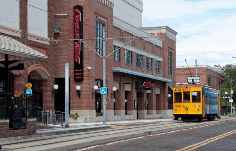 A trolley rolls past a brick building in Ybor City, Florida, housing GameTime Tampa.
